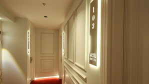 A hallway with a red carpet, a door, and a wall with a sign that reads "AXU HOTEL." - Axu Airport Hotel (Arnavutköy)