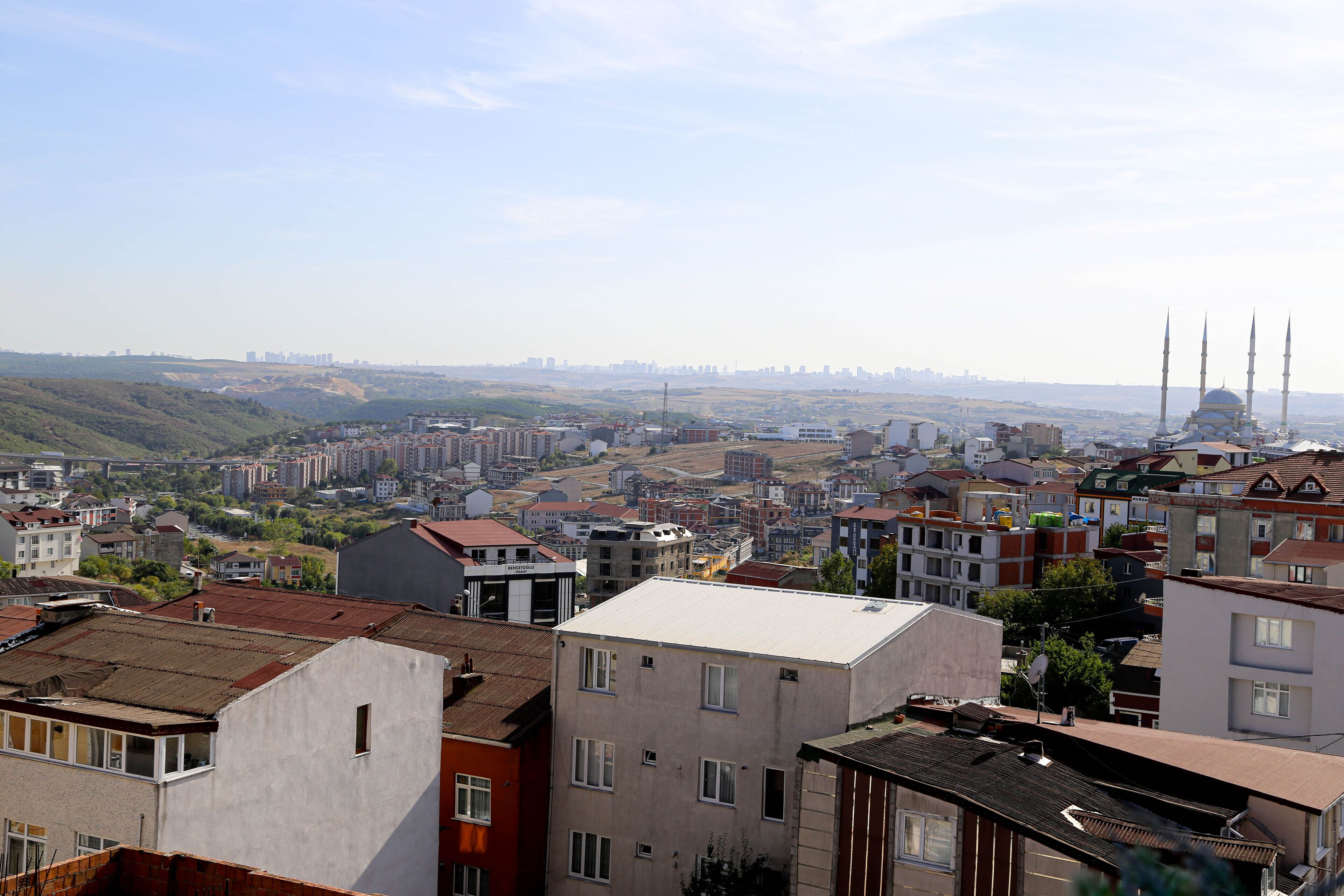 Un paisaje urbano con una combinación de edificios residenciales y comerciales, incluyendo una mezquita destacada con cuatro minaretes.