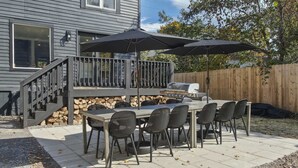 Eine Terrassenanlage im Freien mit Grill, Esstisch und Stühlen.