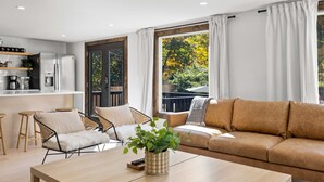 Ein modernes Wohnzimmer mit Sofa, Sesseln, Couchtisch und Küchenzeile.