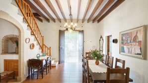 A dining area with wooden furniture, a chandelier, and a staircase.