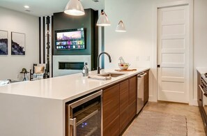 A modern kitchen with a large island, built-in oven, and a flat-screen TV mounted above the island. - Fall nights near Belmont Mansion: music-themed house, sleeps 10, 3BR (Nashville)