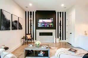 Ein modernes Wohnzimmer mit Kamin, einer Wand-TV und Kunstwerken an den Wänden.