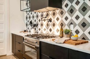 A modern kitchen with a gas stove, oven, and a backsplash with a geometric pattern.