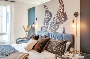 A modern bedroom with a large bed, decorative pillows, a wall art piece, and a bedside table with a lamp. - Fall nights near Belmont Mansion: music-themed house, sleeps 10, 3BR (Nashville)