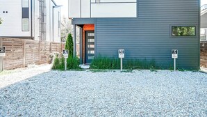 A modern two-story building with a gravel driveway and a wooden fence. - Nashville music-themed house sleeps 10 near Belmont Mansion (Nashville)
