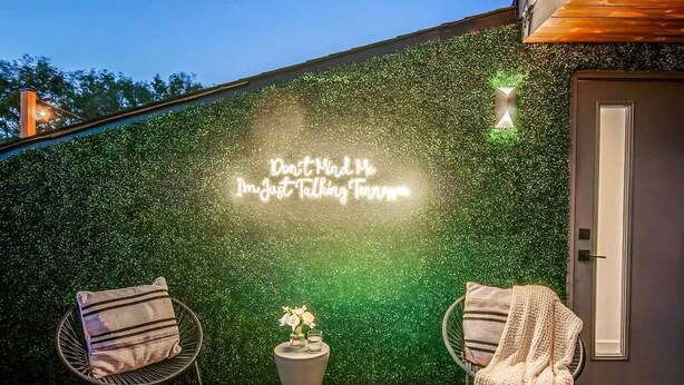 An outdoor seating area with two chairs and a table, a wall with a green textured surface, and a neon sign. - Nashville music-themed house sleeps 10 near Belmont Mansion (Nashville)