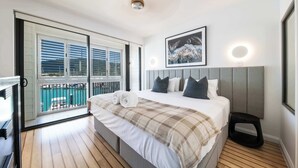 Camera da letto con un letto, una testiera, una finestra con persiane, un balcone e una lampada a soffitto.