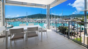 Un balcón con vistas a un puerto deportivo, muebles blancos y un ventilador de techo.