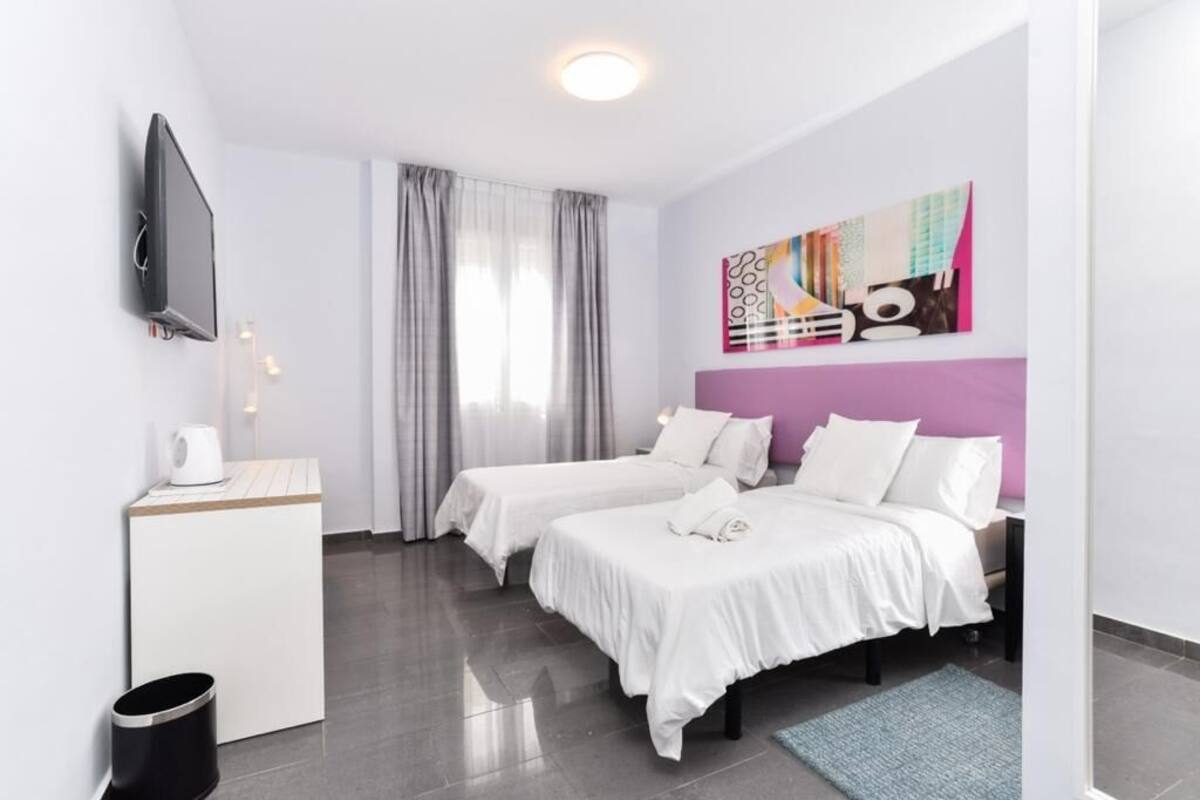 Une chambre d’hôtel moderne équipée de deux lits, d’un téléviseur à écran plat, d’une machine à café et ornée d’un tableau au mur.