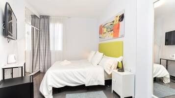Una habitación de hotel moderna con una cama, mesitas de noche, un televisor y un espejo grande.
