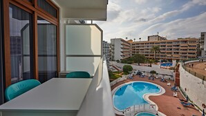A balcony with a pool, lounge chairs, and a dining area with chairs.