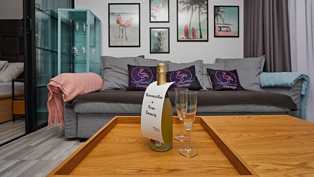 A modern living room with a sofa, a glass cabinet, and a wooden table with a bottle of champagne and two glasses.