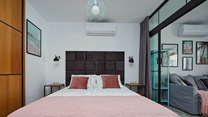 A modern bedroom with a large bed, a dark headboard, and a glass door leading to a balcony.