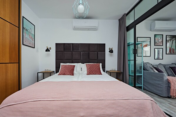 Un dormitorio moderno con una cama grande, cabecera oscura y puerta de cristal que da a un balcón.