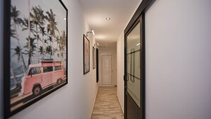 A hallway with wooden flooring, framed artwork, and a sliding door.
