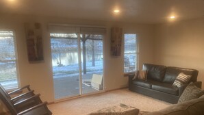 A living room with a black leather sofa, a rocking chair, and a beige couch.