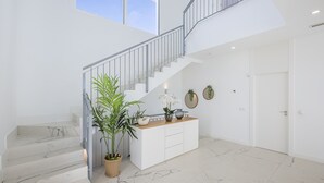 Een modern interieur met een marmeren trap, een witte receptiebalie en een grote potplant.