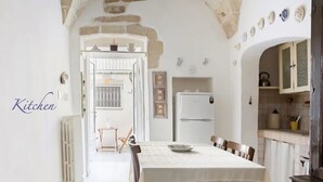 A kitchen with a dining table, chairs, a refrigerator, and a stove.