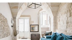 A living room with a stone wall, a blue sofa, a wooden chest, and a framed picture on the wall.
