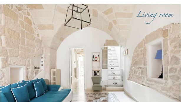 A living room with a stone wall, a blue sofa, a patterned rug, and a white cabinet with drawers.
