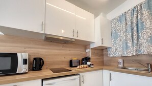 A compact kitchen with a microwave, coffee maker, toaster, and a small sink.