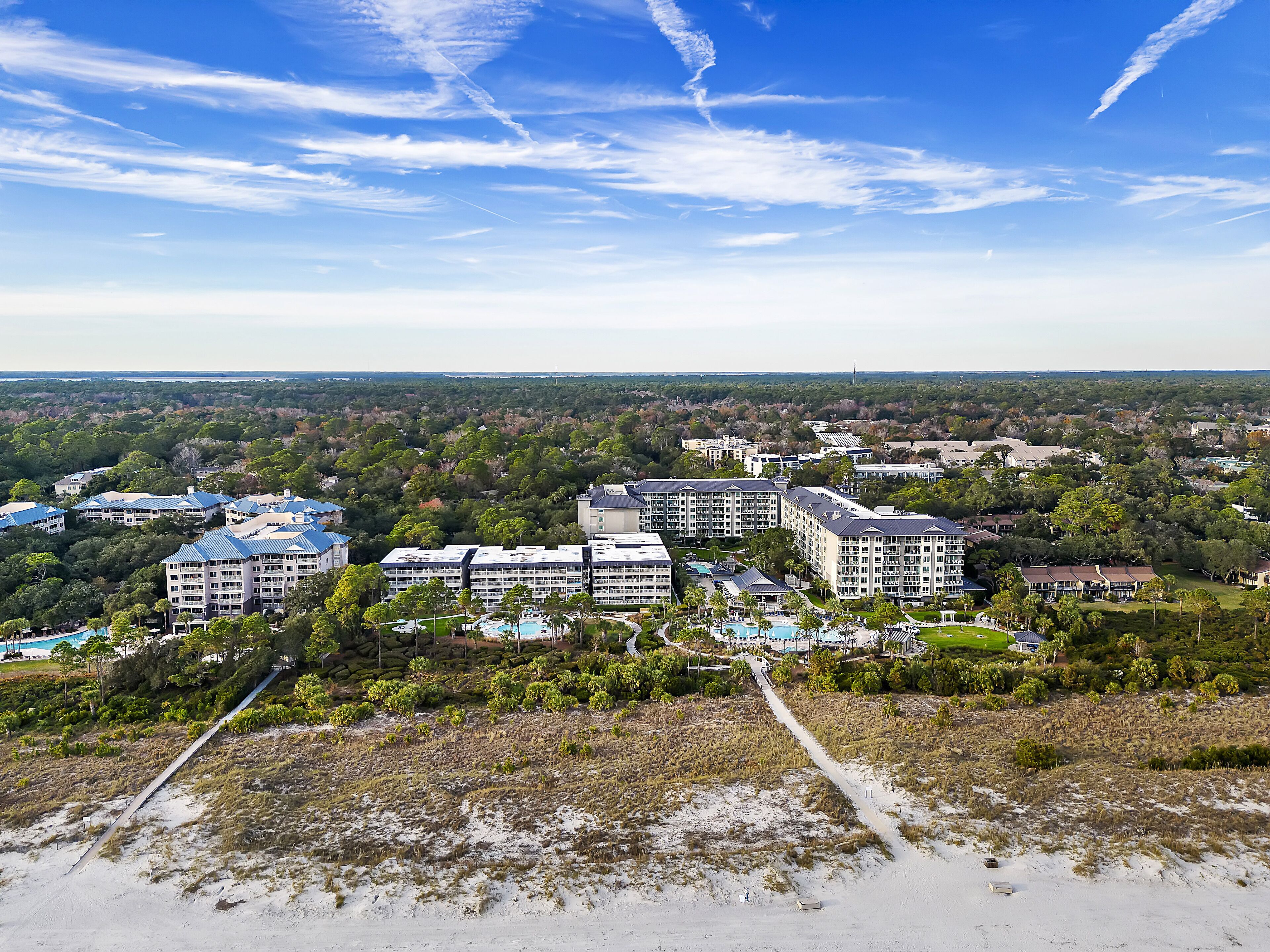 A resort with multiple buildings, a swimming pool, and a beach area.