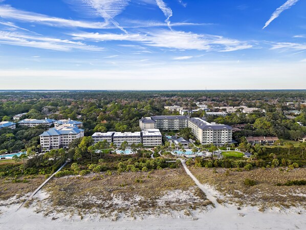 A resort with multiple buildings, a swimming pool, and a beach area.