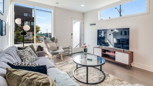 A modern living room with a sofa, armchair, and a TV on a stand. - Perch - Dayton Dream: Cozy and Modern Home | Parking and City View (Seattle)
