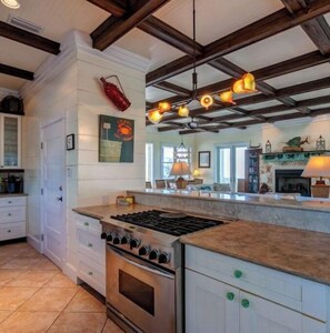 Kitchen features a central island with a stove and oven, white cabinetry, and a tiled floor.