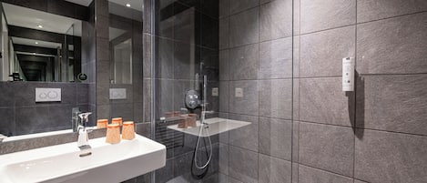 A modern bathroom with a large mirror, a sink, and a shower area.