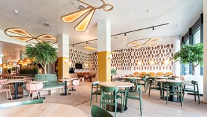 Een modern interieur met ronde tafels en stoelen, decoratieve verlichting en een patroonbehang.