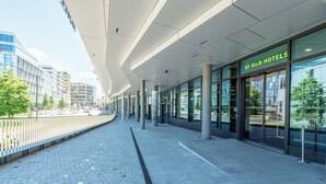 Een moderne hotelentree met een glazen gevel, een heldere lucht en een verhard pad.