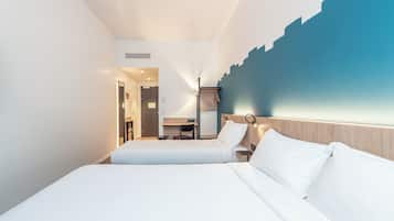 Ein Hotelzimmer mit zwei Betten, einem Schreibtisch und einem Stuhl.