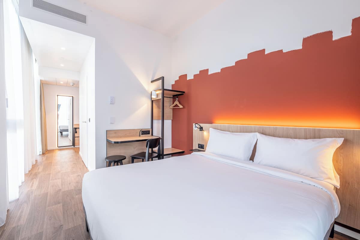 Moderni hotellihuone, jossa on suuri sänky, työpöytä ja tuoli.