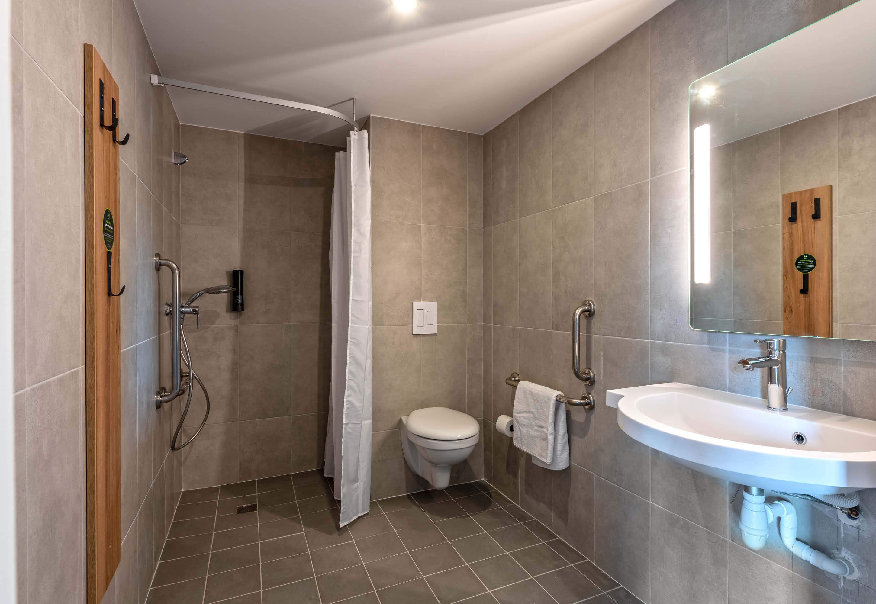 A modern bathroom with a shower, toilet, and sink.