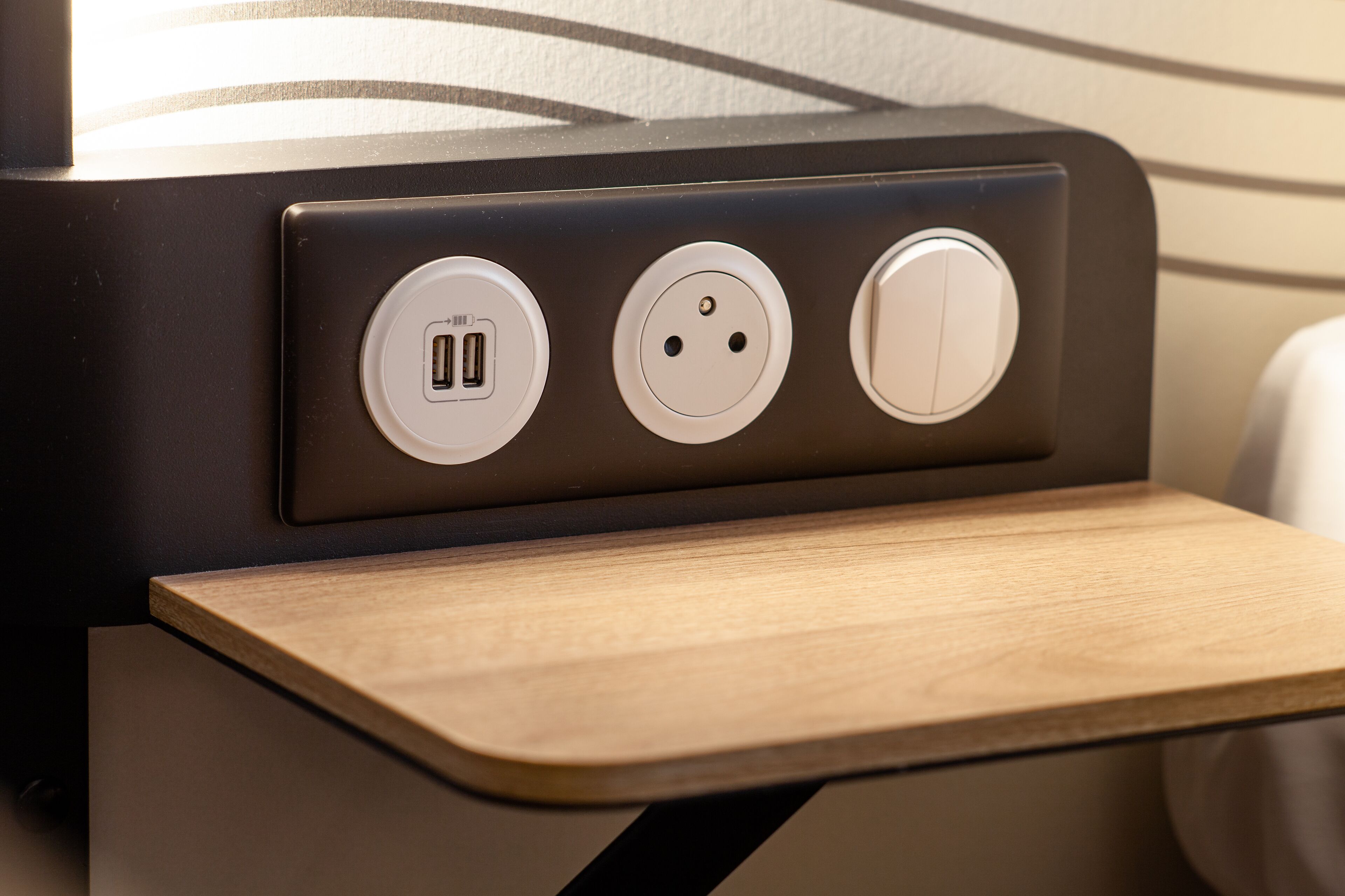 A wall-mounted electrical outlet with a USB port, a standard electrical outlet, and a switch.