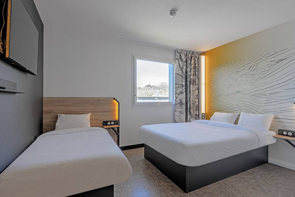 Een moderne hotelkamer met twee bedden, een groot raam en een opvallend wandontwerp.
