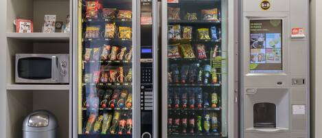 A vending machine area with snack and drink options, a microwave, and a trash bin.