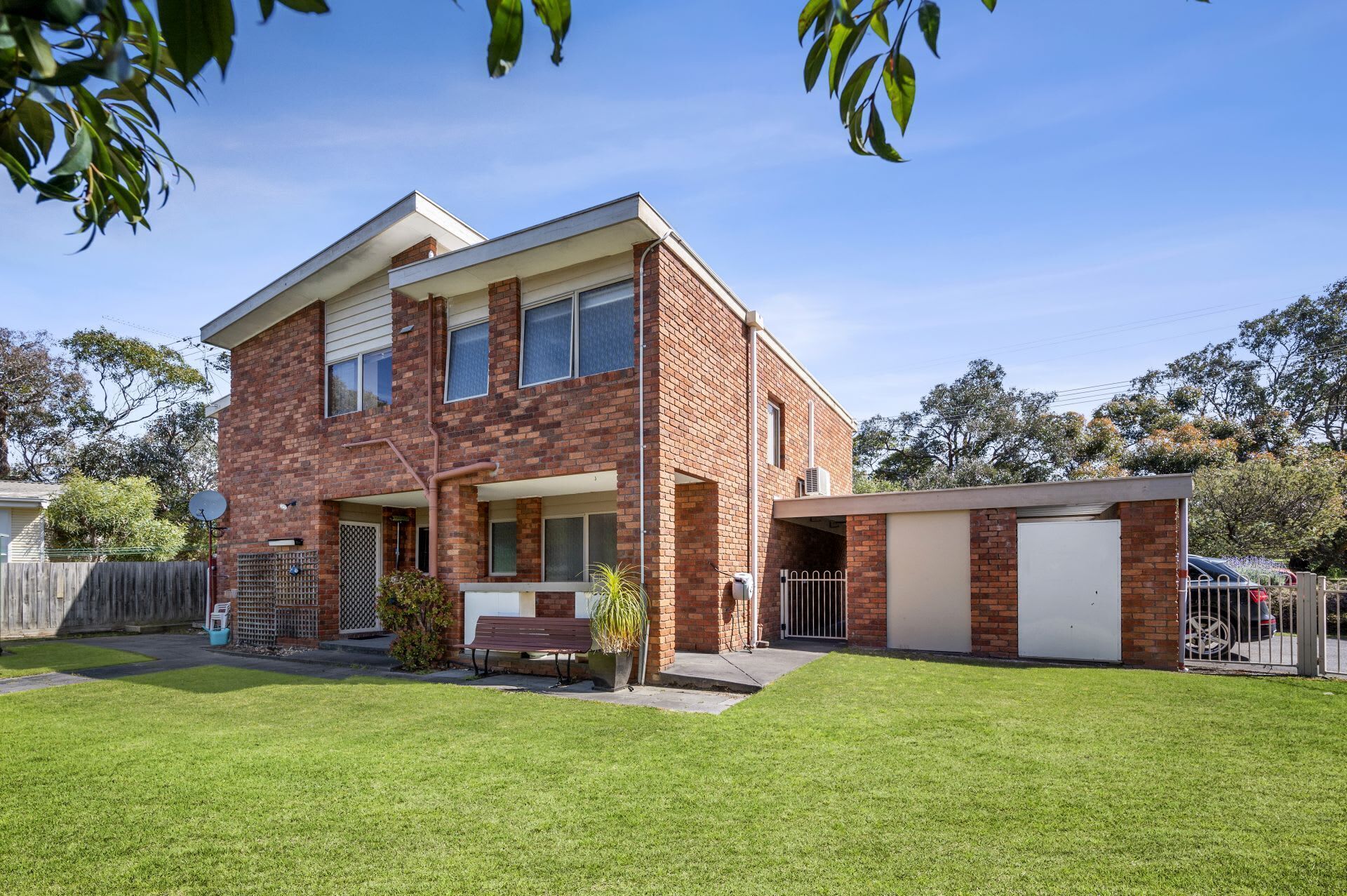 A two-story brick house with a front porch, a garage, and a well-maintained lawn.