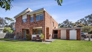 A two-story brick house with a front porch, a garage, and a well-maintained lawn. - 22 Golf Links Road (Anglesea)