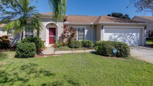 A single-story house with a red door, a garage, and a well-maintained lawn. - Bright Titusville Retreat w/ Lanai - WFH Friendly! (Titusville)