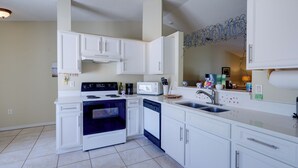 A modern kitchen with white cabinets, a stove, microwave, and dishwasher. - Bright Titusville Retreat w/ Lanai - WFH Friendly! (Titusville)