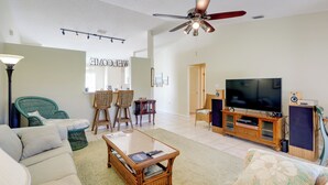 A living room with a sofa, chairs, a coffee table, a television, and a ceiling fan. - Bright Titusville Retreat w/ Lanai - WFH Friendly! (Titusville)