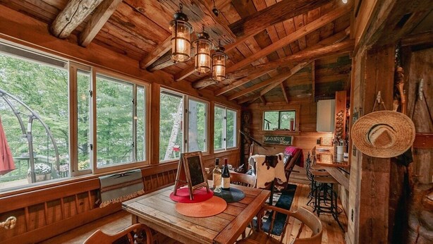 Un interno rustico in legno con ampie finestre, un tavolo di legno e una statua di mucca.