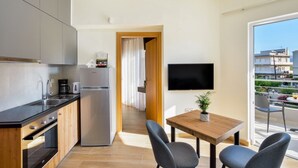Une cuisine moderne équipée d’un réfrigérateur, d’une cuisinière et d’un évier. On y trouve également un coin repas avec une table et des chaises, ainsi qu’un téléviseur fixé au mur.