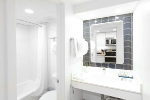 Un baño moderno con ducha, inodoro y tocador con espejo.