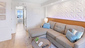 A modern living room with a grey sectional sofa, a round coffee table, and a decorative wall panel.