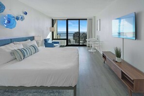 A modern hotel room with a large bed, a balcony with a view, a flat-screen TV, and a desk with a plant. - Casa Palmera By Casanita - Small-Dog Friendly Suite (Myrtle Beach)