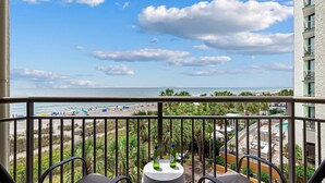 Un balcon avec vue sur la plage, deux bouteilles de bière et une table.